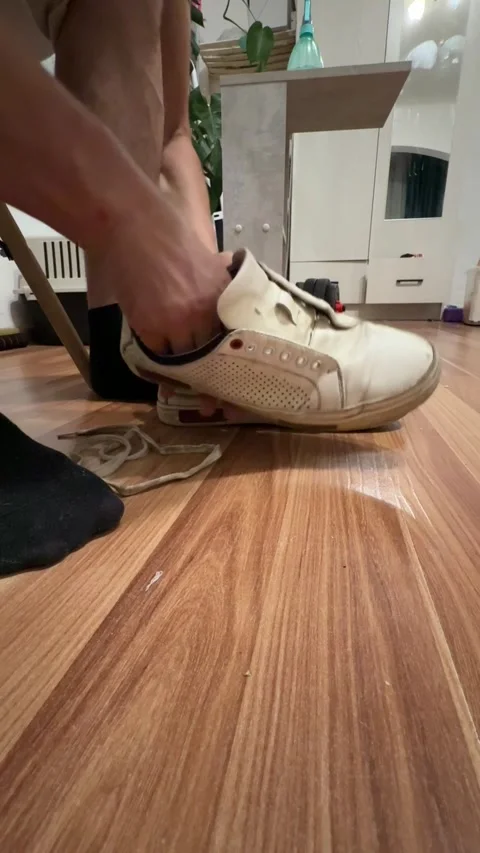 Man's hands close-up threading shoelaces into white sneakers on wooden floor Stock Footage 337354990