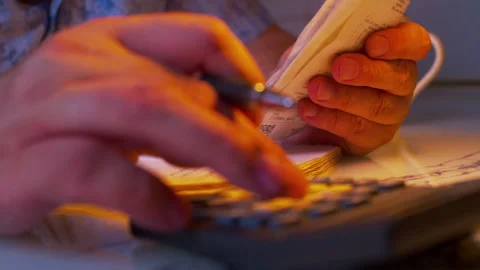 A man's hands copying financial data from paper receipts into a notebook Stock Footage 336976461