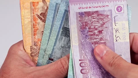 Mans hands counting brand new Malaysian ringgit (MYR) banknotes. Stock Footage 300031187