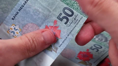 Mans hands counting brand new Malaysian ringgit (MYR) banknotes. Stock Footage 300034729