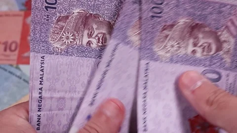 Mans hands counting brand new Malaysian ringgit (MYR) banknotes. Stock Footage 300051481