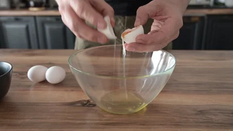 Mans hands cracking eggs into bowl to separate yolks from whites Stock Footage 341855263