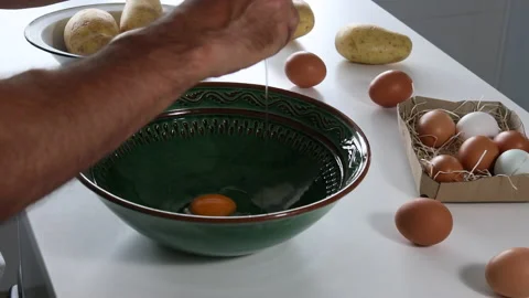 Man's hands cracking eggs to prepare a Spanish omelette. Video stock 197117805