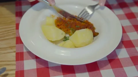 The man's hands cut off a piece of white stewed fish with a knife and take a Stock Footage 162497311
