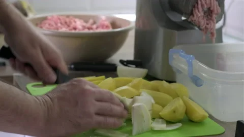 Mans hands cut potatoes and onion with the knife in the kitchen closeup. Cooking Video stock 165059860