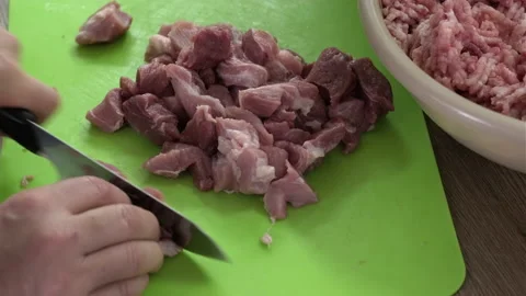 Mans hands cut raw meat with the knife in the kitchen closeup. Preparation of Stock Footage 165058859