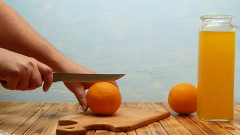 Man's hands cuts orange on cutting wooden board of home in kitchen. Stock Footage 204137163