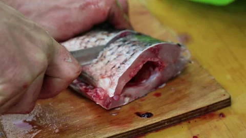 A mans hands cutting fish with a knife on a wooden board, close-up Stock Footage 312595132