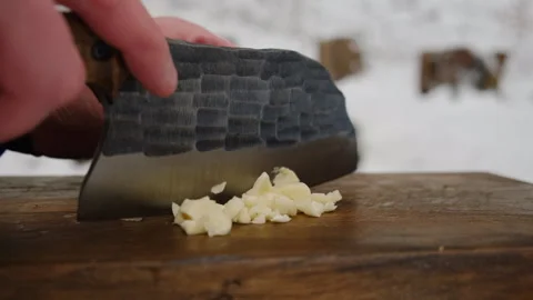 Man's hands cutting garlic with knife at nature. Cooking outdoors concept Stock Footage 308706986