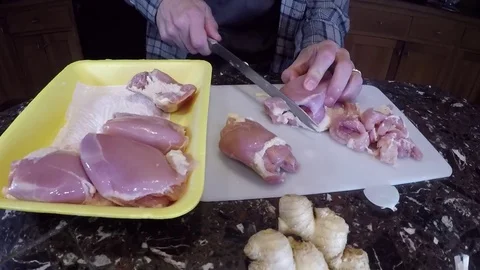 Man's hands cutting up raw chicken thighs Video stock 73025929