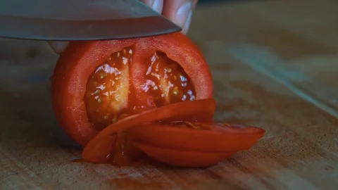 Man's hands cutting tomato, behind fresh vegetables. Sliced Tomatoes in Half. Stock Footage