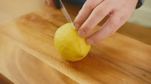 Man's Hands Cutting Whole Lemon With Knife On Chopping Board Stock Footage 86069901