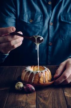 Man's hands decorating traditional Easter ring cake with glaze Stock Photos