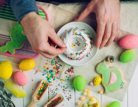 Man's hands decorating traditional Easter ring cake with sugar sprinkles Stock Photos