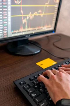 Man's hands on the desktop computer keyboard analyzing the stock market and c Stock Photos