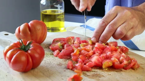 Man's hands dicing fresh tomatoes on a wooden board in a kitchen. Stock Footage 195949707