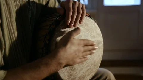Man's hands drumming out a beat on an African skin-covered hand drum. Vidéo 74518921