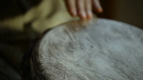 Man's hands drumming out a beat on an African skin-covered hand drum. Video stock 74519113