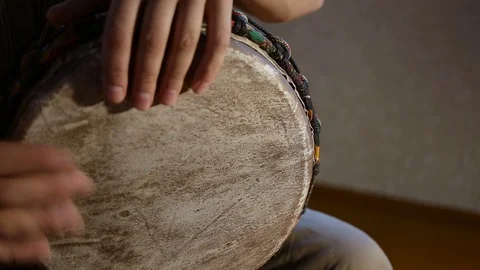 Man's hands drumming out a beat on an African skin-covered hand drum. Stock Footage 74519134