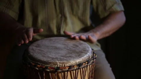 Man's hands drumming out a beat on an African skin-covered hand drum. Stock Footage 74521568