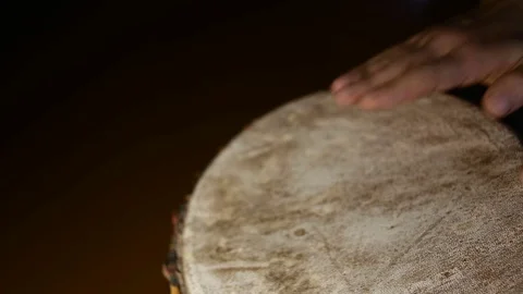 Man's hands drumming out a beat on an African skin-covered hand drum. Video stock 74521891