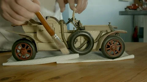 Mans hands dusting light colored antique vintage car model. Time lapse. Stock Footage 73007530