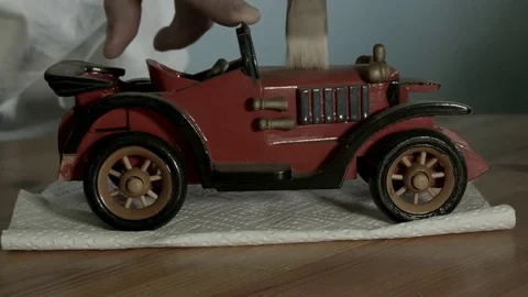 Mans hands dusting a red ceramic antique model car. Not B&amp;W Vidéo 72971777