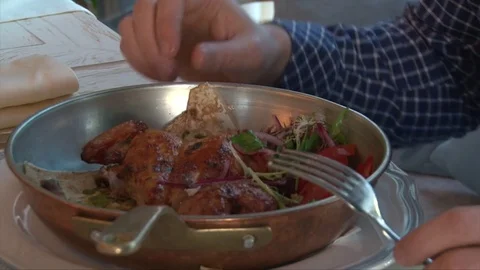Mans hands eating roasted chicken from a pan in a restaurant, closeup shot Stock Footage 72301151