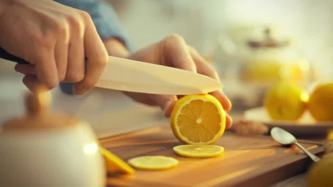 A mans hands expertly slice a fresh citrus lemon on a cutting board amidst a Stock Footage 331314361