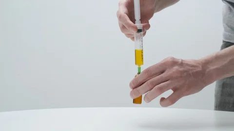 Man's hands filling vial with solution from syringe. doctor preparing vaccine Stock Footage 128799526