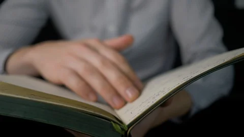 Man's hands flipping through the book, lying on his knees. 4K Stock Footage 94101274