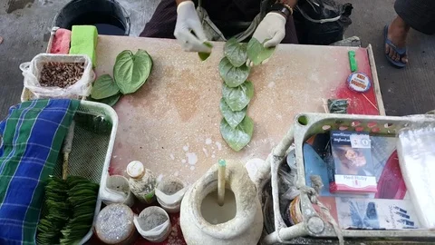 Man’s hands in gloves prepare leaves for traditional chewing tobacco and betel Видео 77836880