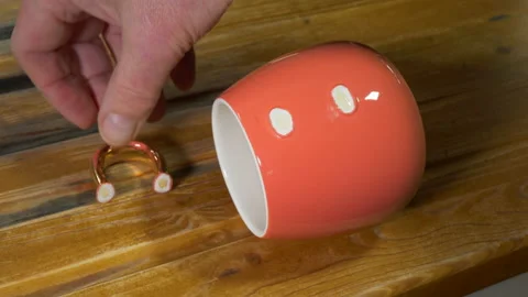 A man's hands gluing the handle back in place on a broken pink cup / mug. Video stock 167281263