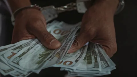 Man's hands in handcuffs hold a wad of money. hands with handcuffs holding Stock-Footage 336260509