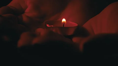 Man's Hands Hold a Candle in Red Lighting Dark Close-up Stock Footage 244215136