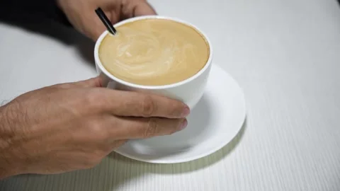 A man's hands hold delicious coffee in a white cup on a white table Stock Footage 292833766