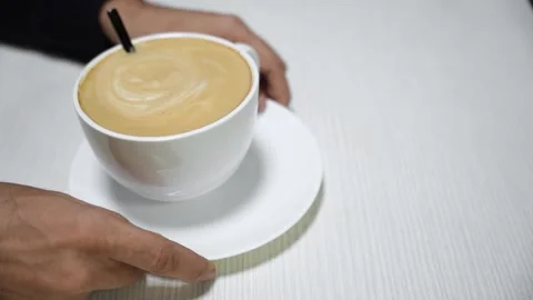 A man's hands hold delicious coffee in a white cup on a white table Stock Footage 292833874