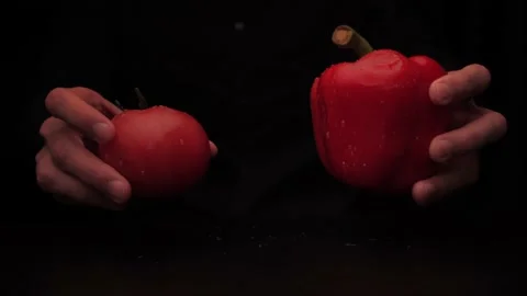 A man's hands hold out red pepper and tomato from the darkness Stock Footage 142863757