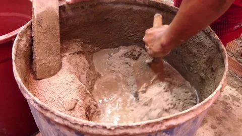 Man's hands hold a shovel while making a mixture of cement, sand, and water. Video stock 153451990