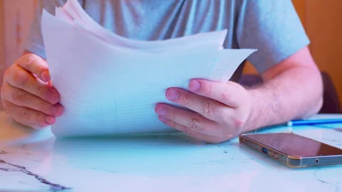 A man's hands holding and flipping through a stack of paper documents. Stock Footage 336693706
