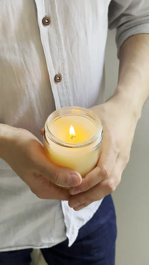 Man's hands holding burning candle in glass jar, decorative container candle Stock Footage 242498448