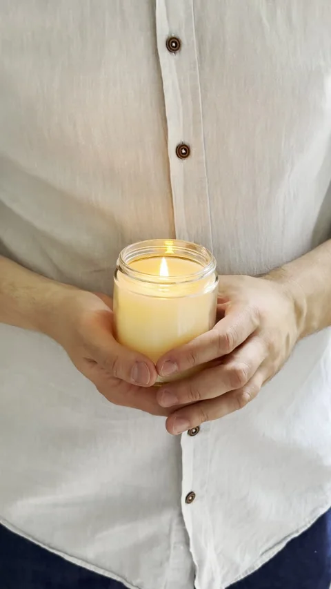 Man's hands holding burning candle in glass jar, decorative container candle Stock Footage 242501775