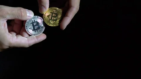 Man's hands holding golden and silver Bitcoin on black background Stock Footage