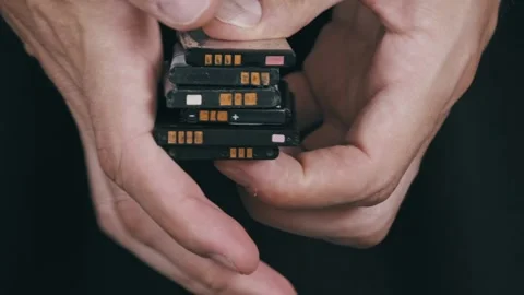 Mans Hands Holding a Stack of Used Mobile Phone Batteries. Stock Footage 315795872