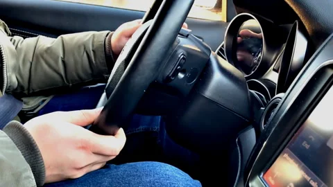 Mans hands holding steering wheel driving car with blurred city street lights at Stock Footage 281331183