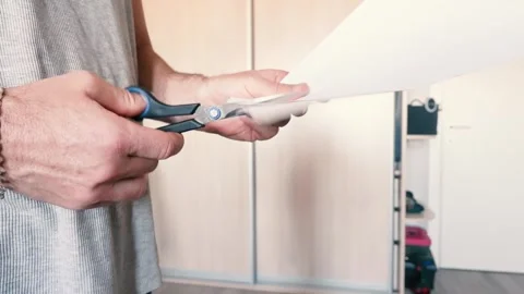 Man's Hands Holding a White Sheet of Paper and Cutting It with Scissors Video stock 342095854