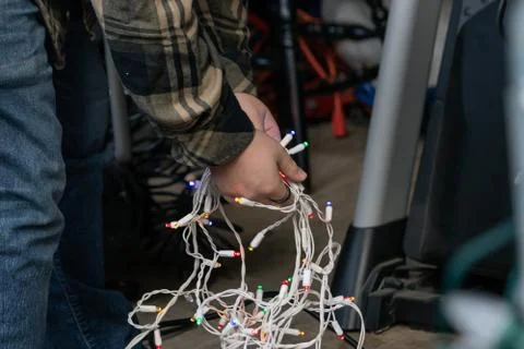 Mans hands holding white strings of colorful christmas lights ready to decorate Stock Photos