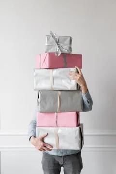 In the mans hands is a huge stack of packed holiday boxes, gray and pink colo 写真素材