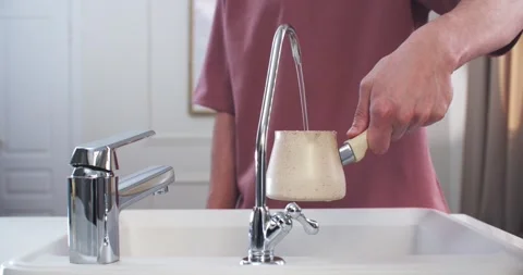 Man’s hands in the kitchen draw filtered water into a coffee machine. Vidéo 230644826