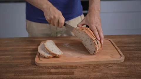 Mans hands with knife cutting bread on wooden board. Close-up, homemade. Stock Footage 316285801